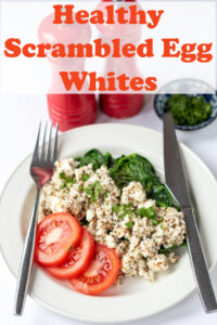 Healthy scrambled egg whites served on a plate of spinach with sliced tomatoes. Knife to left side. Fork to the right. Pin title text overlay at top.