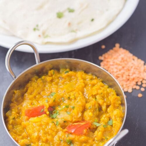 Birds eye view of a balti dish of Indian dahl with Naan breads on a plate.