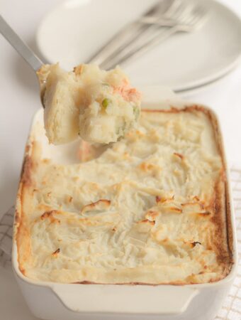 Easy fish pie just taken out of the oven with a spoon lifting a portion out.