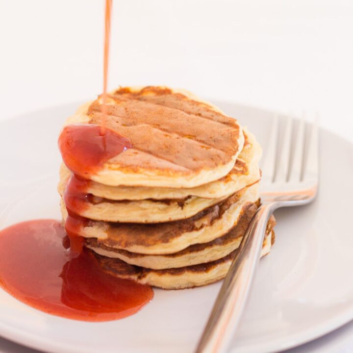 A stack of Scottish porridge oat pancakes on a plate with syrup being poured over.