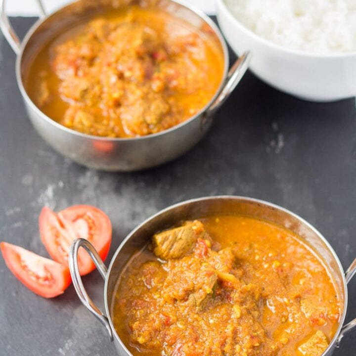Two balti dishes of beef curry casserole with a dish of rice to the side.