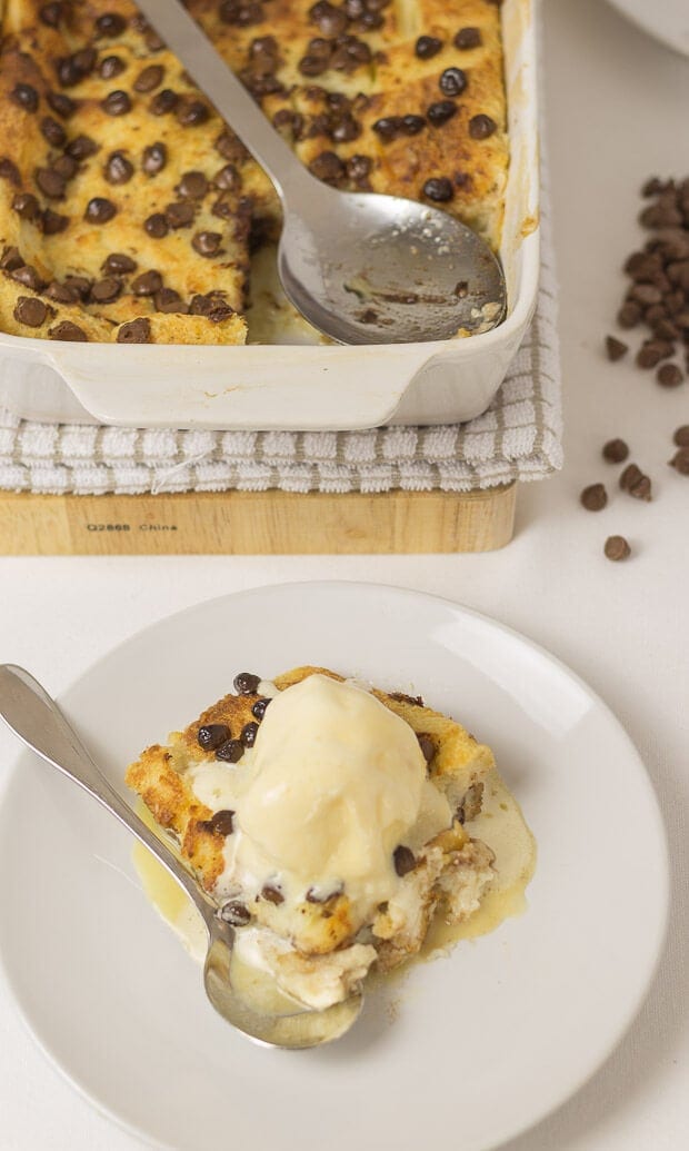 A portion of chocholate chip bread and butter pudding served with ice cream on top. Rest of the dish at the top of the photograph.