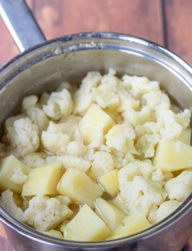 Cooked potatoes and cauliflower in a saucepan.