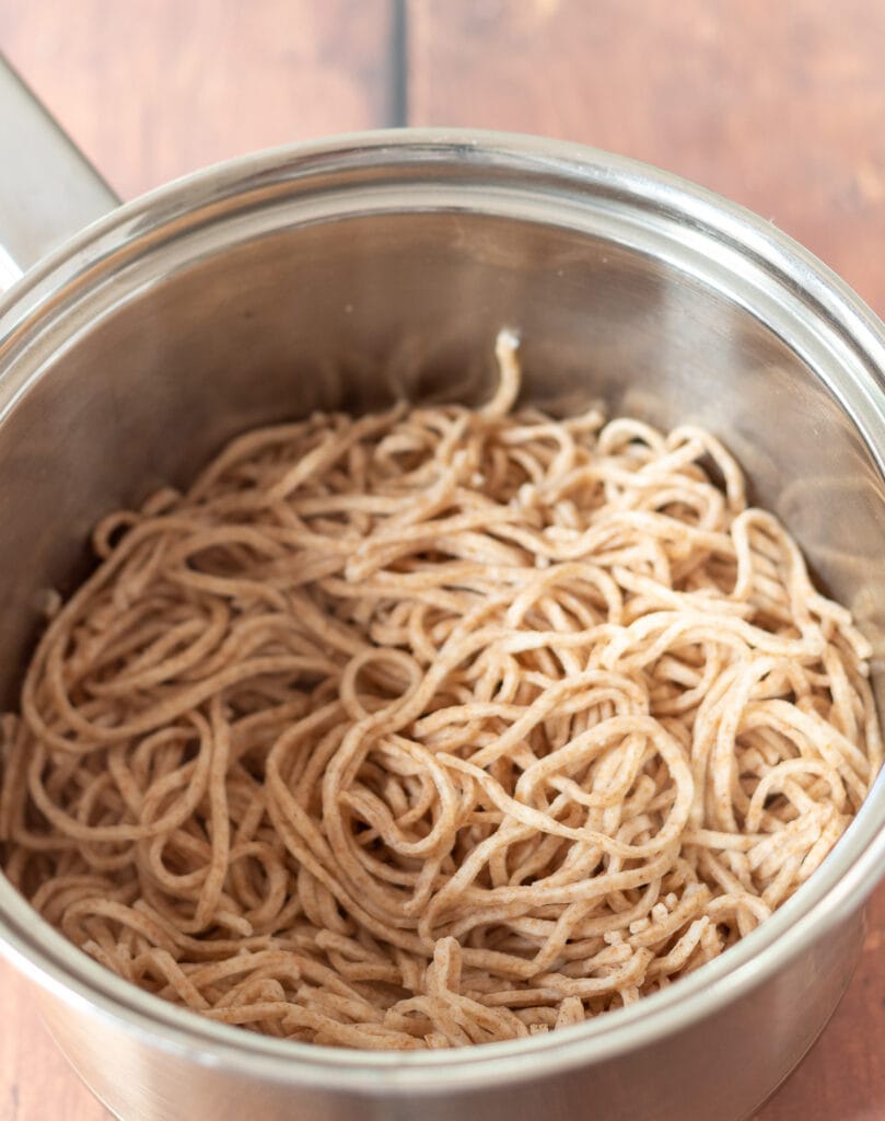 Cooked wholewheat noodles in a saucepan.