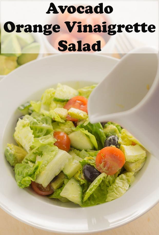 A bowl of avocado salad with a jug of orange vinaigrette being poured over. Pin title text overlay at top.