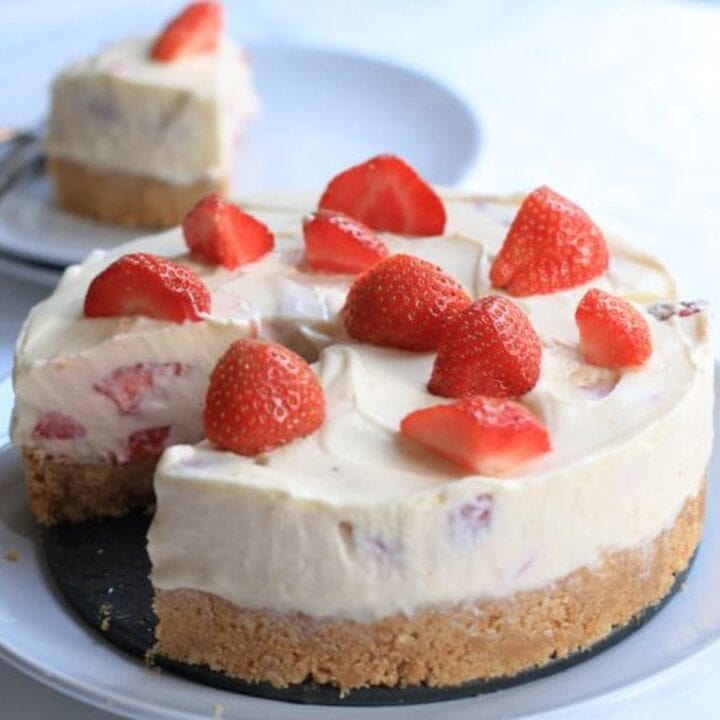 Strawberry whisky cheesecake on a plate with a slice removed and served on a plate in the background.