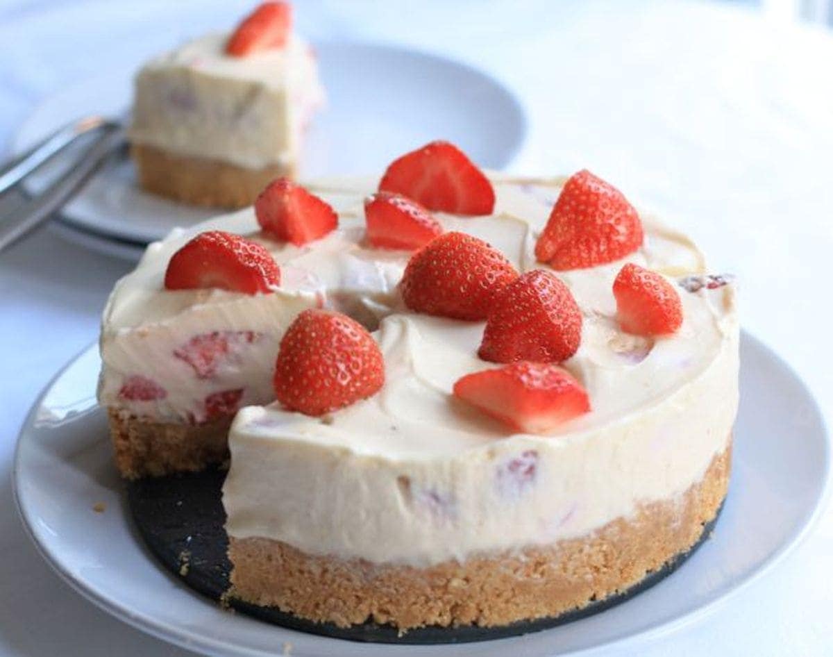 Strawberry whisky cheesecake on a plate with a slice removed and served on a plate in the background.