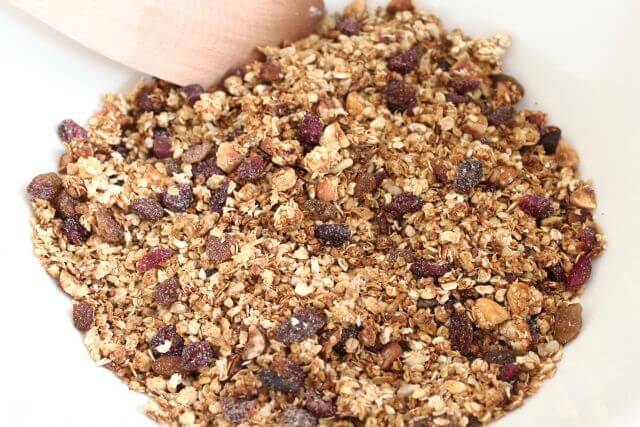 Healthy homemade granola finished and being mixed together in a large bowl.