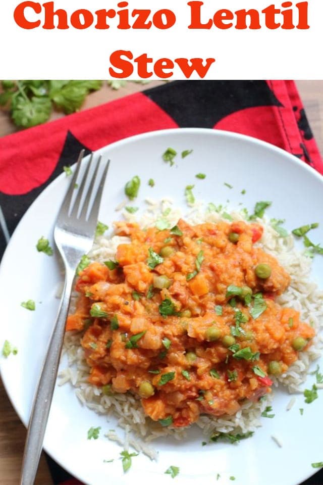 Birds eye view of a plate of chorizo lentil stew garnished with chopped parsley and a fork to the left hand side.