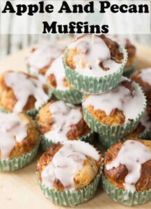Apple and Pecan Muffins stacked on a round chopping board. Pin title text overlay at top.
