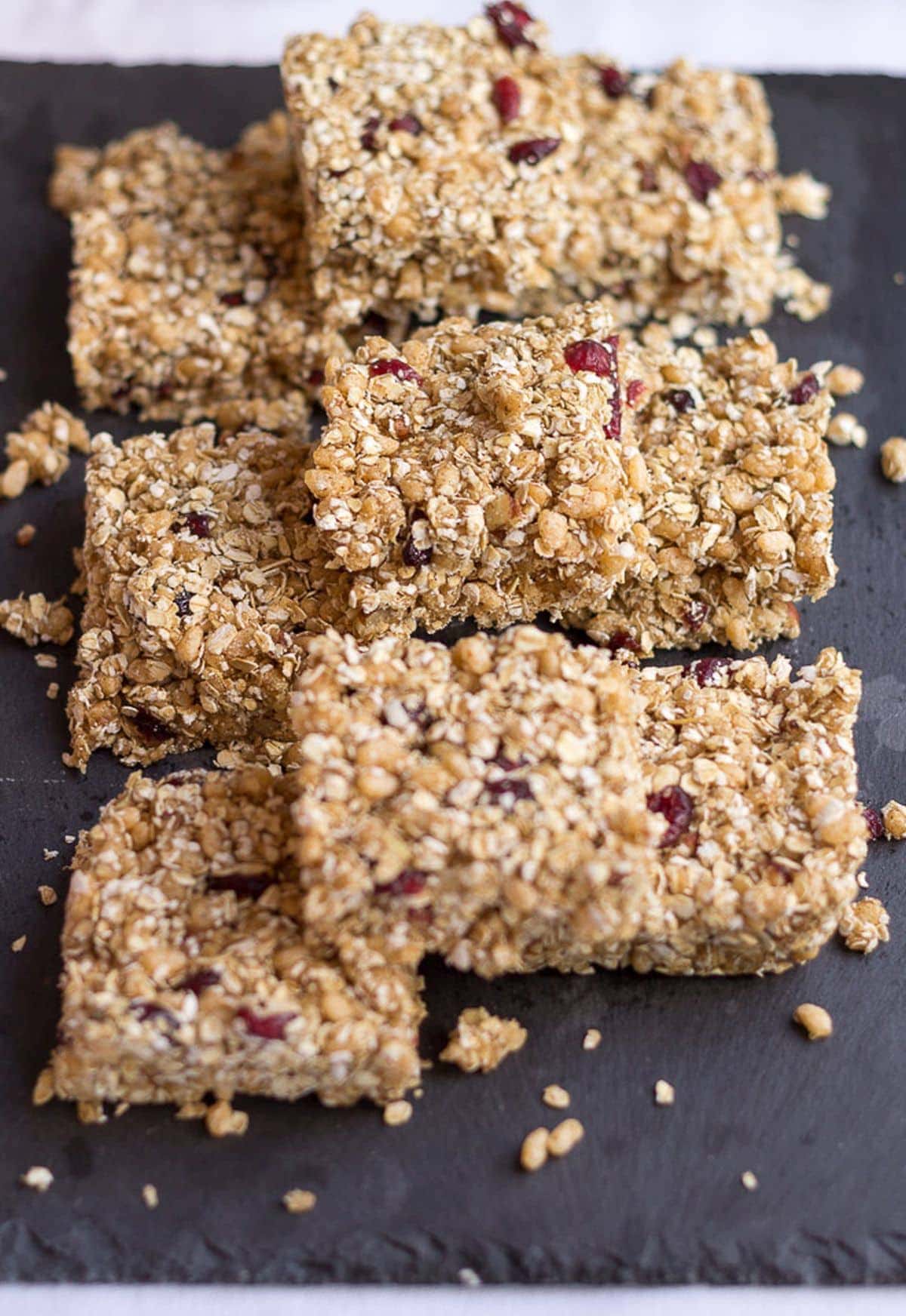 No bake cranberry flapjacks stacked in a line on a black square slate.