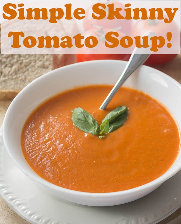 A bowl of skinny tomato soup garnished with 2 basil leaves and with a spoon in ready to eat.