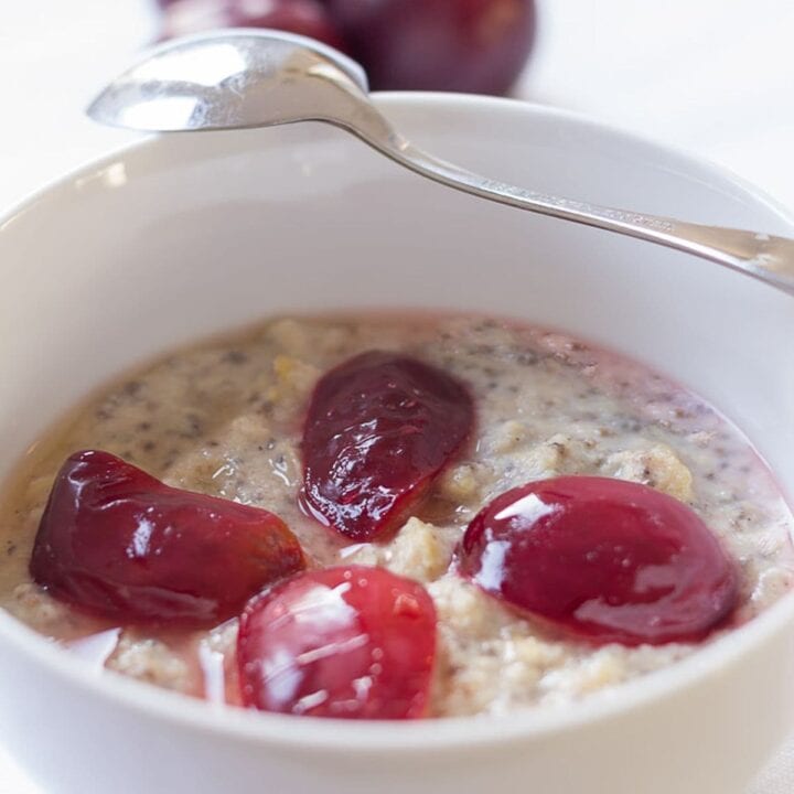A bowl of spiced plum millet porridge with a spoon laid over the top.