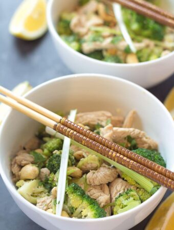 Two bowls of turkey and broccoli stir fry one in front of the other with chopsticks on. Lemon wedges to the side of the bowls.