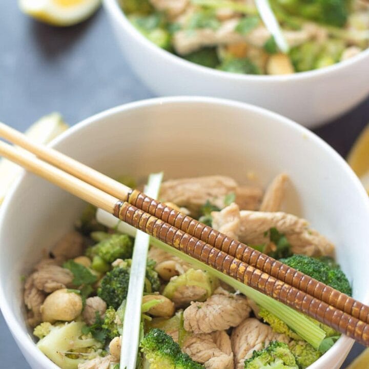 Two bowls of turkey and broccoli stir fry one in front of the other with chopsticks on. Lemon wedges to the side of the bowls.