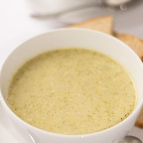 A bowl of broccoli and stilton soup with a spoon in front of it.