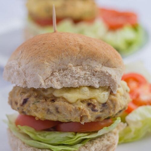 Two healthy turkey burgers one in front of the other on burger buns garnished with salad.