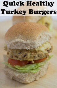 Tow quick healthy turkey burgers one in front of another on a chopping board.
