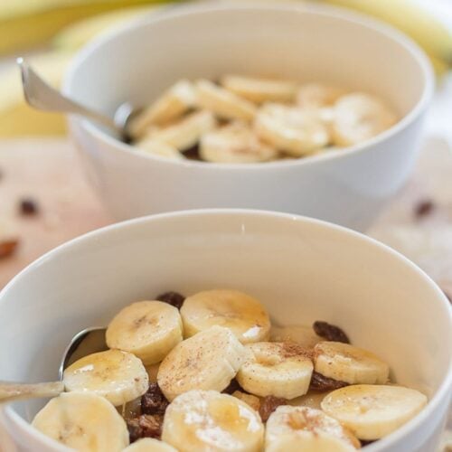 Two bowls of semolina breakfast porridge one in front of the other decorated with sliced bananas.