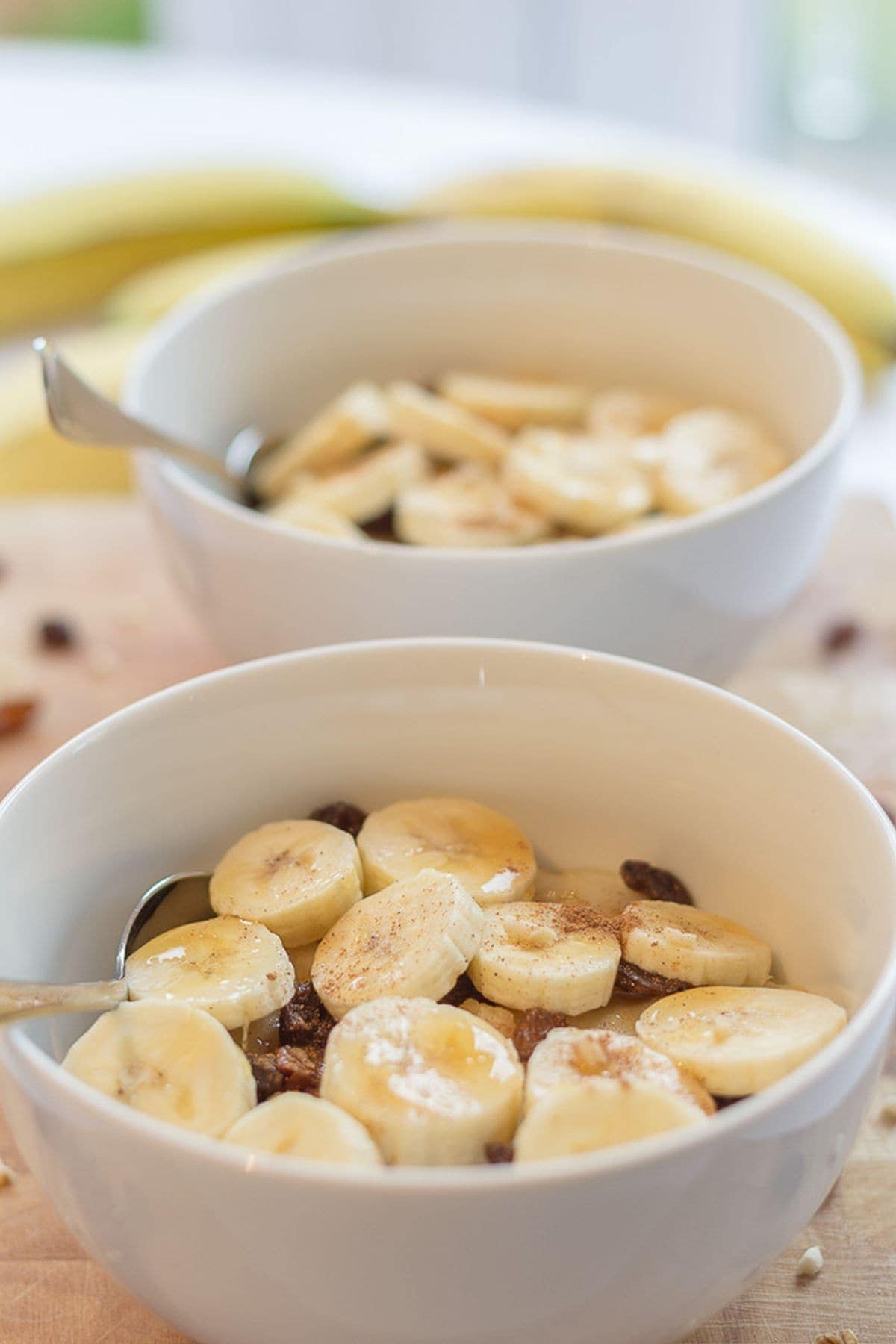 Two bowls of semolina breakfast porridge one in front of the other decorated with sliced bananas.