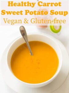 A garnished bowl of healthy carrot and sweet potato soup with a spoon in ready to eat.