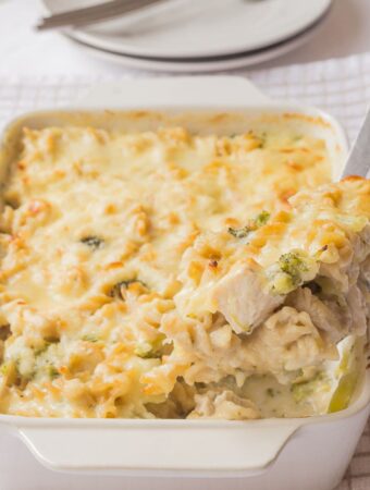 A slice of chicken broccoli stilton pasta bake being lifted from the cooked casserole dish.