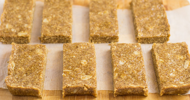 Eight bars of no-bake almond oat bars laid out on a chopping board.