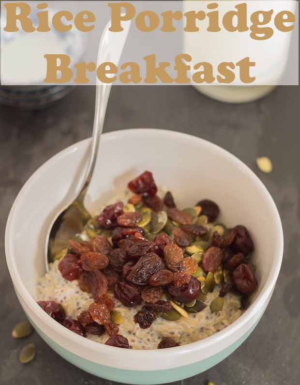 A bowl of rice porrige breakfast topped with dried fruits and seeds. With a spoon in ready to eat. Pin title text overlay at top.