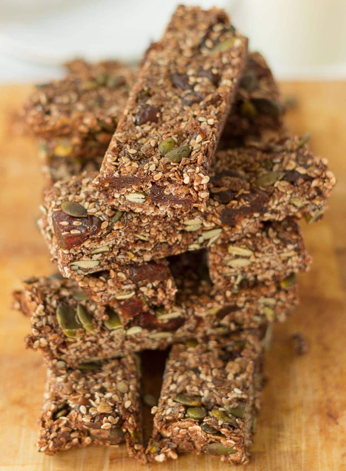 No bake breakfast granola bars stacked one on top of each other on a wooden chopping board.