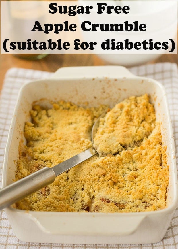 Apple crumble made without sugar in a large serving dish with a spoon placed diagonally across dish. Pin title text overlay at top.