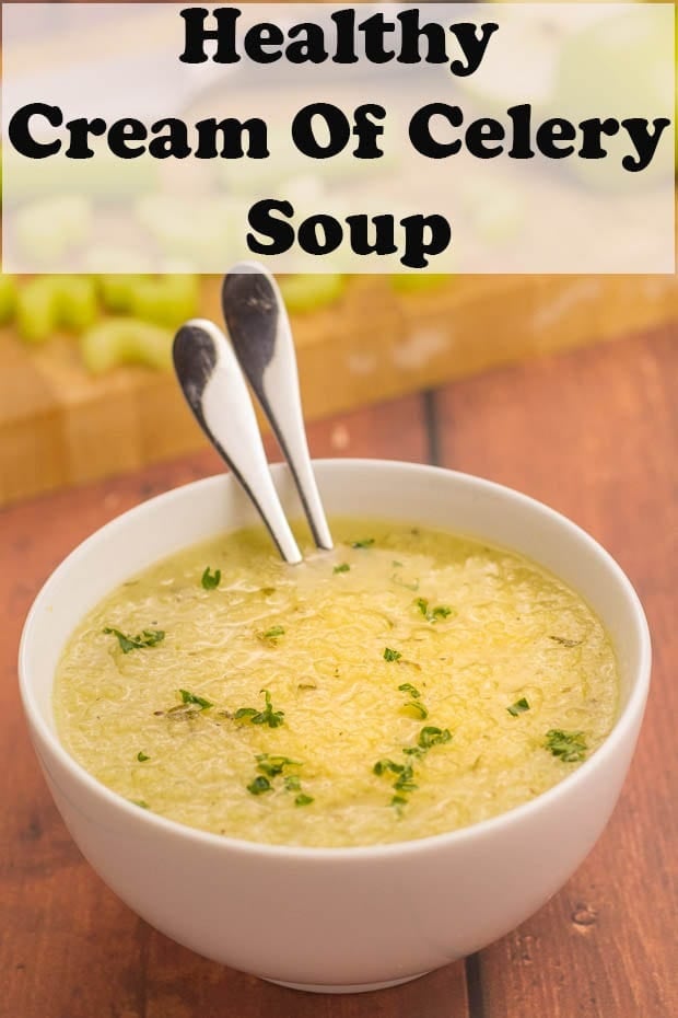 Healthy cream of celery soup served in a bowl with two spoons in and chopping board in the background.