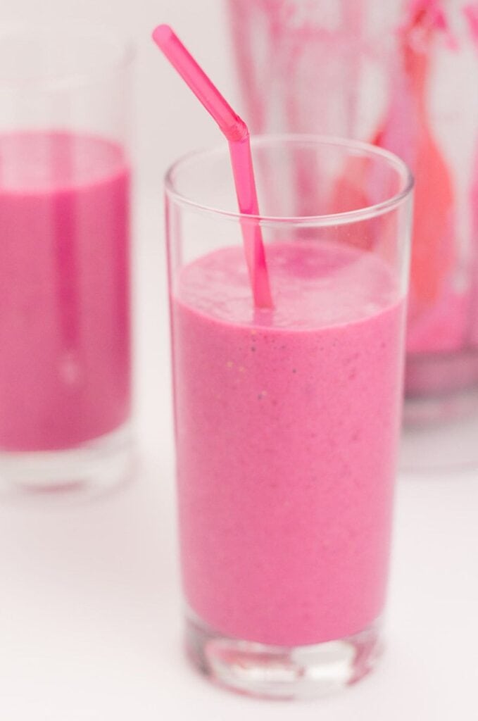 A glass of strawberry beetroot smoothie with a straw in. 