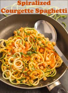 A pan of cooked spiralized courgette spaghetti with serving spoon in. Pin title text overlay at top.