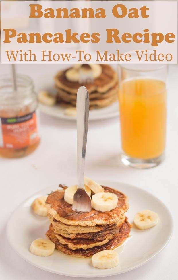 Banana oat pancakes stacked on a plate with a fork in. Orange juice and honey jar in the background.