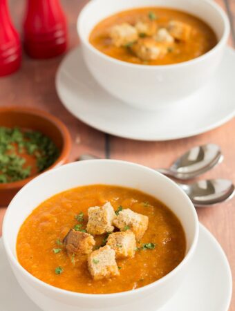 Two bowls of Mediterranean vegetable soup garnished with croutons.