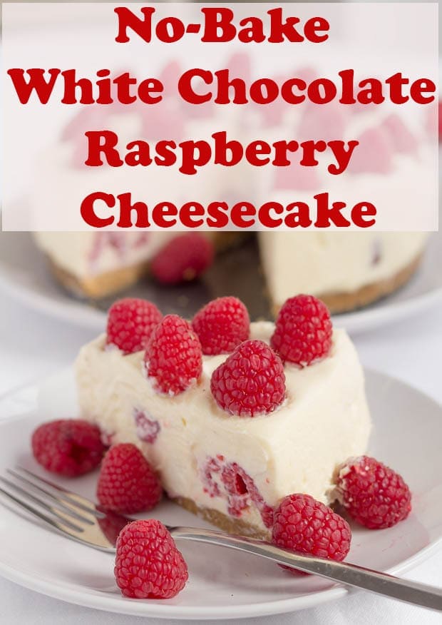 A slice of no-bake white chocolate and raspberry cheesecake on a plate decorated with raspberries and the remainder of the cheesecake in the background.