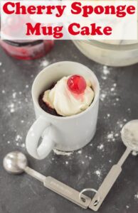 Cherry sponge mug cake decorated with cream and a cherry on top.