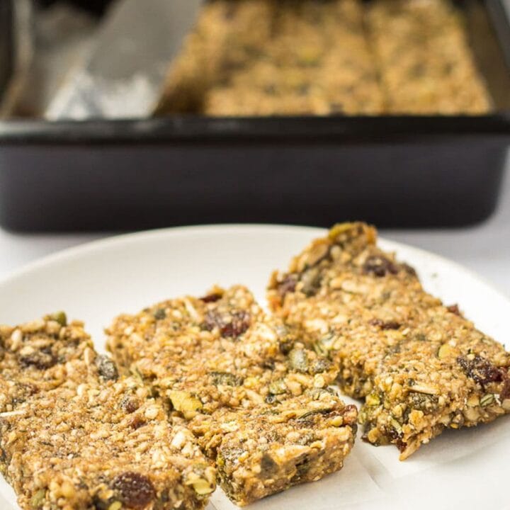 Three no bake banana energy bars on a plate with the rest in a baking dish in the background.