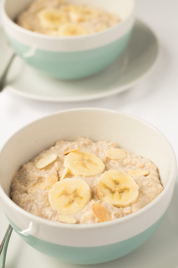 Two bowls of banana almond overnight quinoa one in front of another garnished with sliced banana.