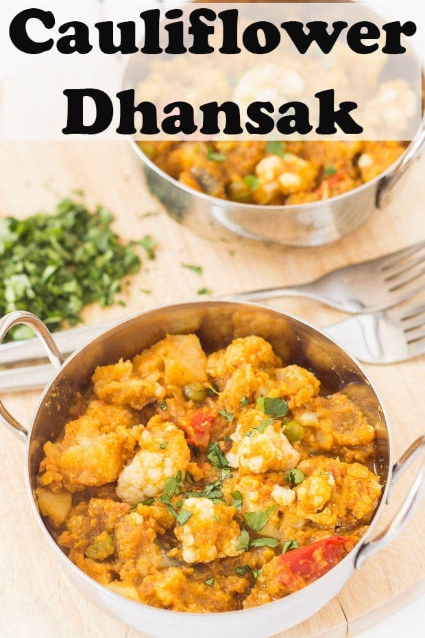 Two balti dishes of cauliflower dhansak one in front of the other with forks to each and coriander to garnish with.