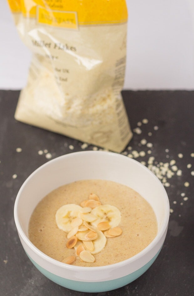 A bowl of banana millet porridge with a bag of millet flakes in the background.