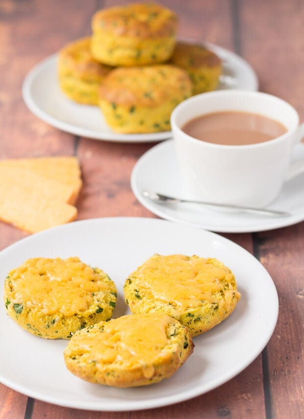 A plate of sweet potato scones with a cup of tea in the background and plate of the rest of the cooked whole scones.