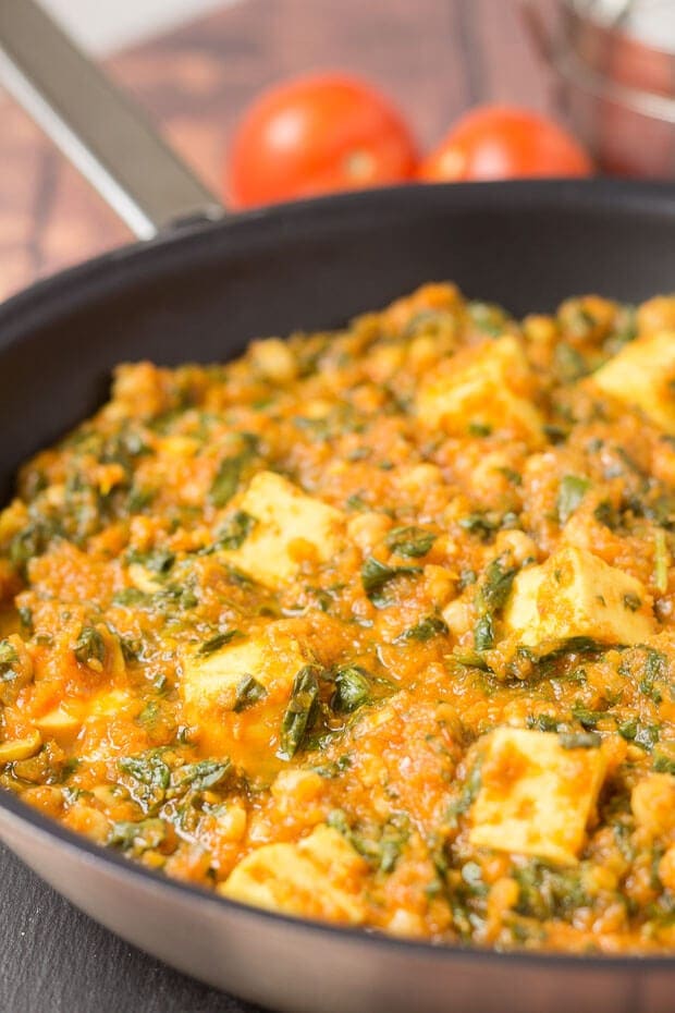 Close up of paneer and chickpea curry cooked in a pan ready to serve.