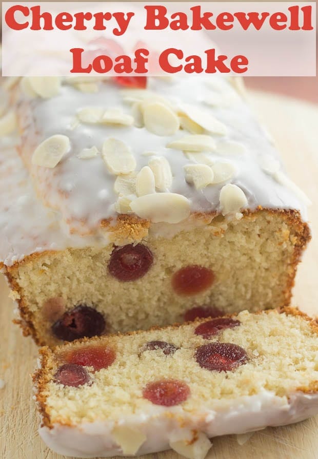 Cherry bakewell loaf cake on a bread board facing forward with a slice cut off and lying in front of the cake so delicious inside filled with cherries can be seen!