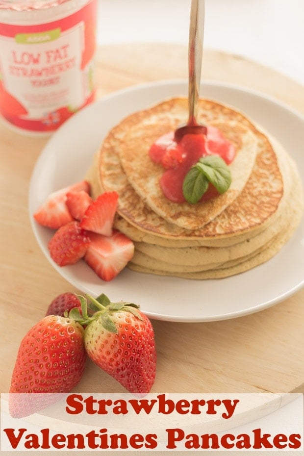 A stack of strawberry valentines panckes on a plate with a fork through. Pin title text overlay at bottom.