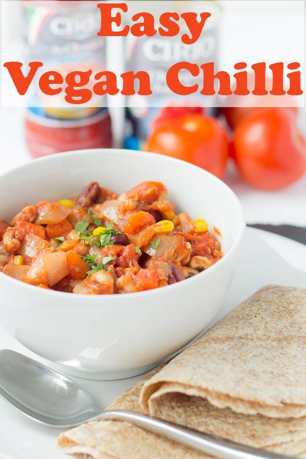 A bowl of easy vegan chilli with wraps beside the bowl and a spoon for serving.