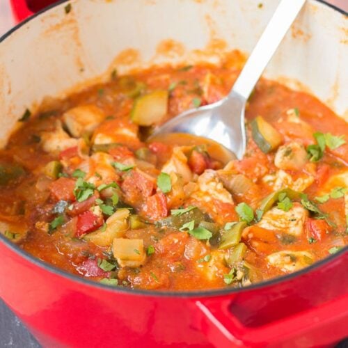 One pot Mediterranean chicken in a large casserole pot with a serving spoon in.
