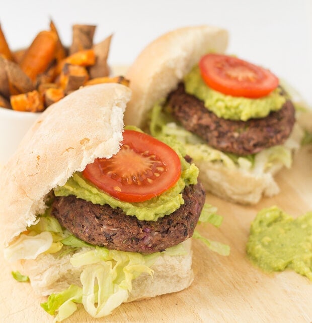 Two quick and easy black bean burgers in burger buns. Sweet potato fries in the background.