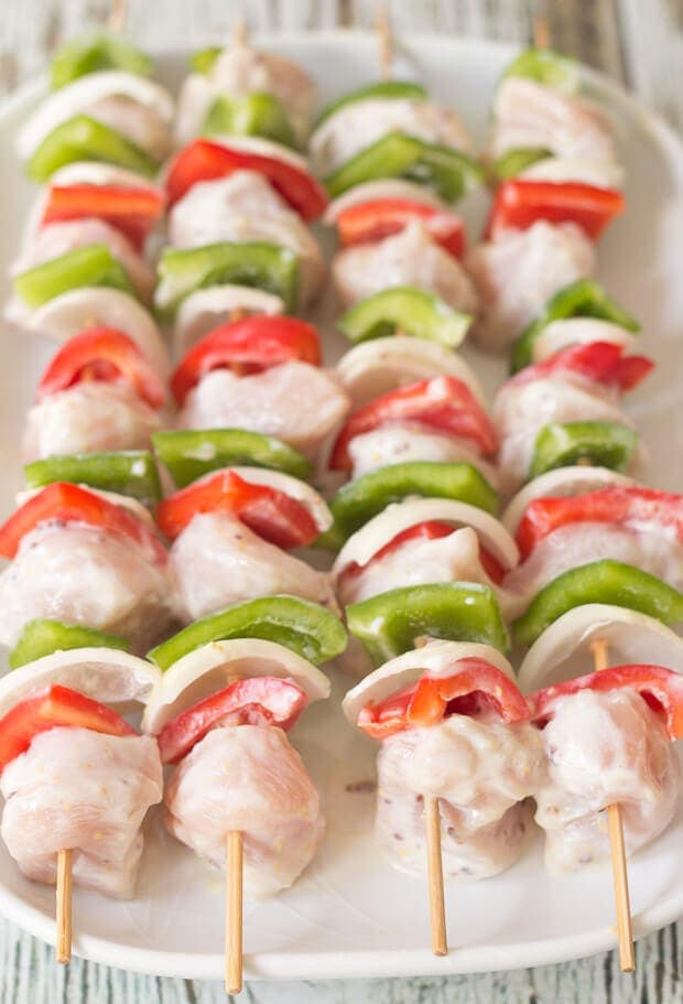 Close up view of four marinated honey mustard chicken skewers.