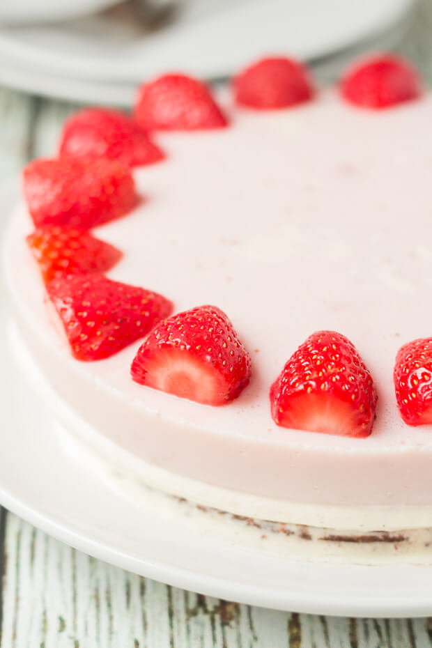 View of half a no bake strawberry mousse cheesecake decorated around the edge with halved strawberries.